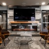 stylish chairs in front of faux fireplace wall with mounted tv in Media Center